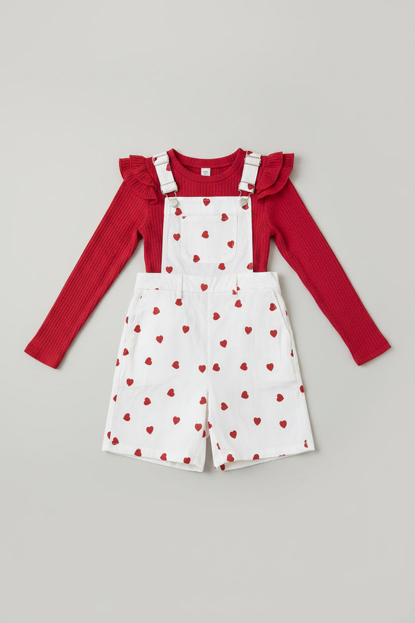 Adorable girls 2-piece suspender shorts set featuring a red ribbed ruffle top and white heart-print overalls. Perfect for Valentine's Day, parties, family photos, and everyday boutique style.