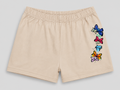 Beige athletic shorts with an elastic waistband and a vertical graphic of colorful embroidered butterflies on the left leg, shown against a neutral gray background.