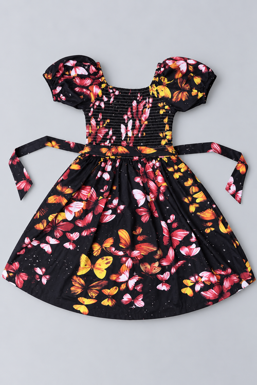 Back view of girls black butterfly print dress with smocked bodice, puff sleeves, tie waist and colorful butterfly pattern