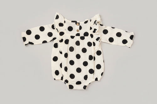 Baby girl black and white polka dot bubble romper featuring lace-trimmed ruffles, long sleeves, and a soft cotton muslin fabric. A timeless boutique outfit for everyday wear, family photos, and special occasions.