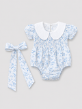 Baby girls white and light blue floral smocked romper with Peter Pan collar and matching floral bow, front view, size 1–3M.