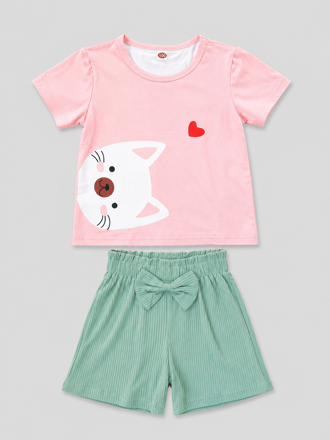 Shop this adorable girls’ 2-piece outfit featuring a pink kitty graphic top with ruffled shoulders and coordinating mint green bow shorts. A sweet and comfortable choice for everyday wear