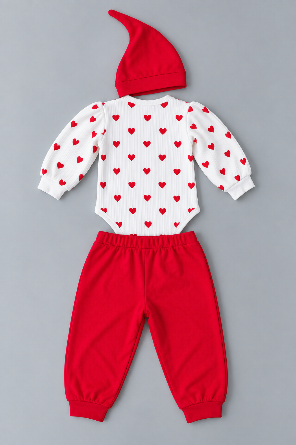 Back view of baby red and white three-piece outfit with heart print romper, solid red jogger pants and matching pointed hat