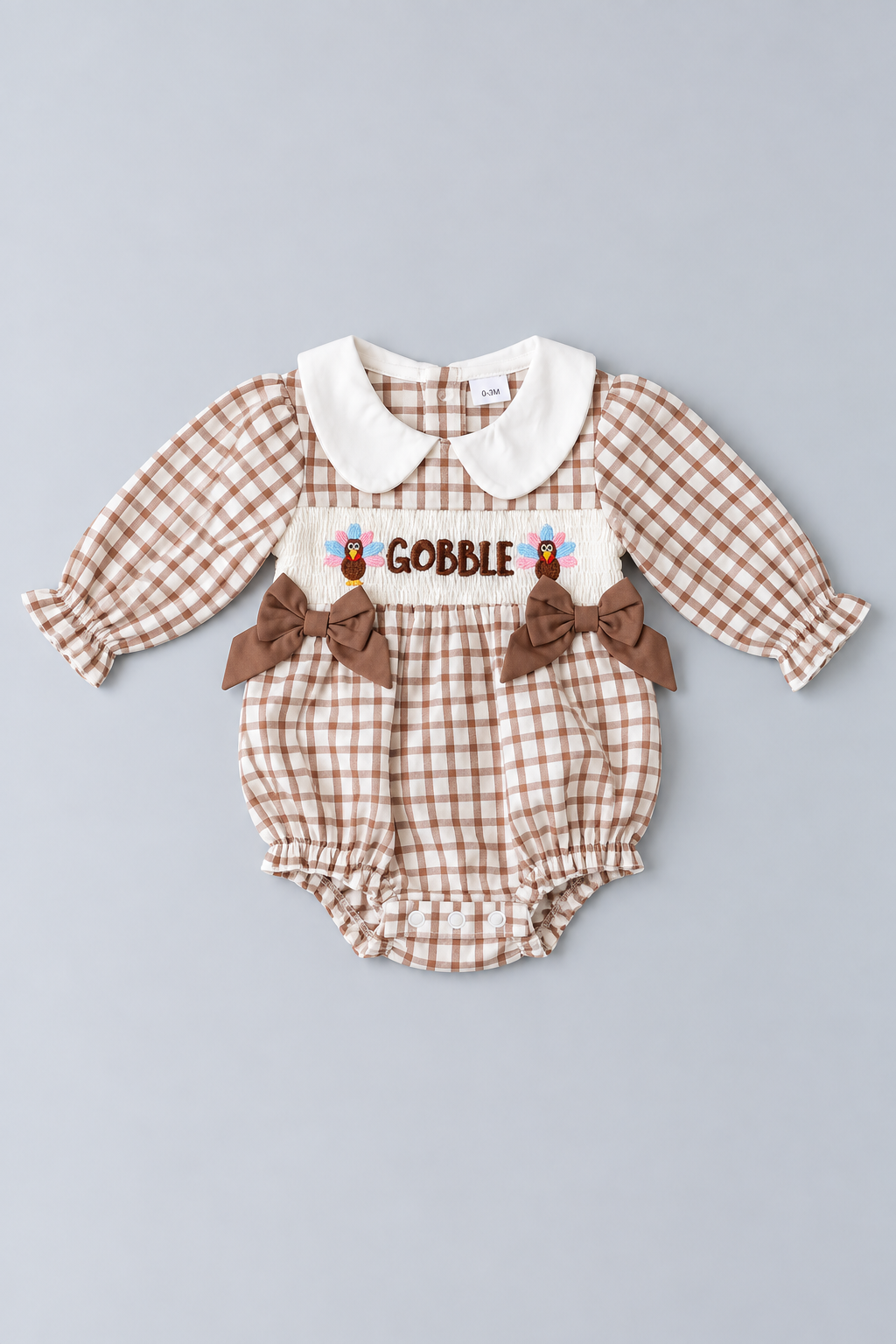 Brown and cream gingham Thanksgiving baby bubble romper with white Peter Pan collar, Gobble turkey embroidery, brown bows and long puff sleeves.