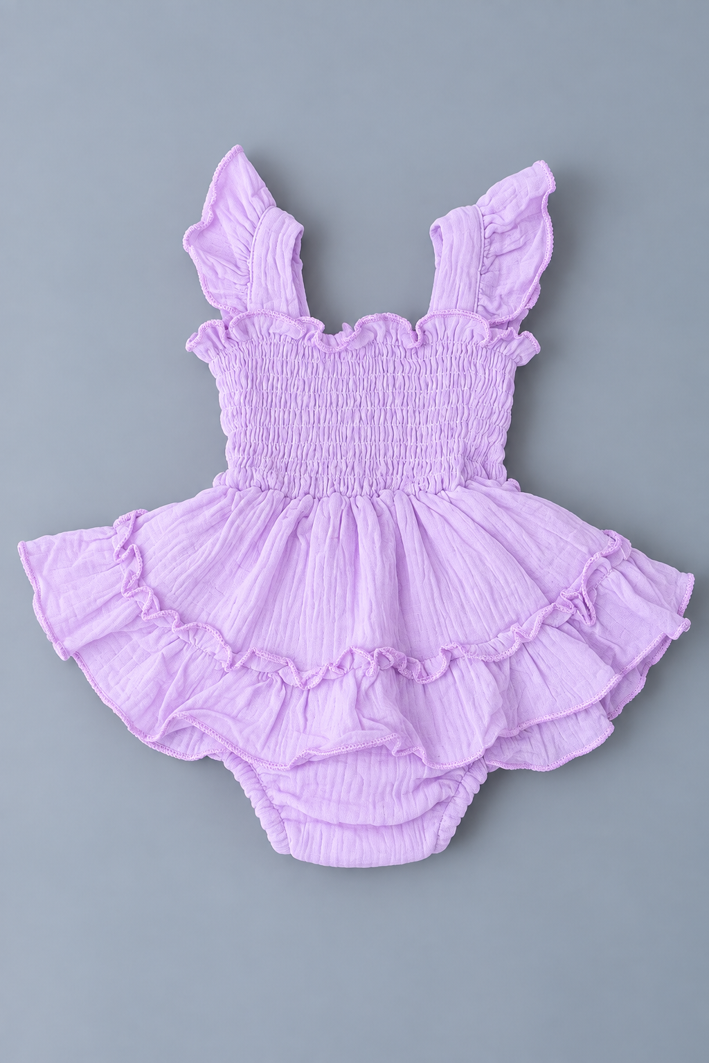 Back view of baby girl lavender skirted romper with smocked bodice, flutter straps and layered ruffle skirt
