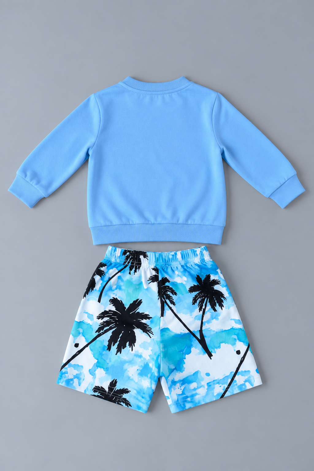 Back view of boys solid blue sweatshirt and tropical palm tree print shorts two-piece outfit