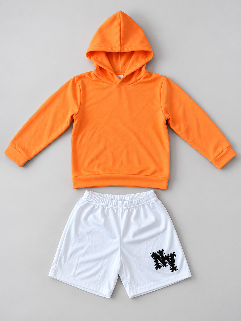 Kids orange pullover hoodie and white NY graphic shorts two-piece outfit, front view