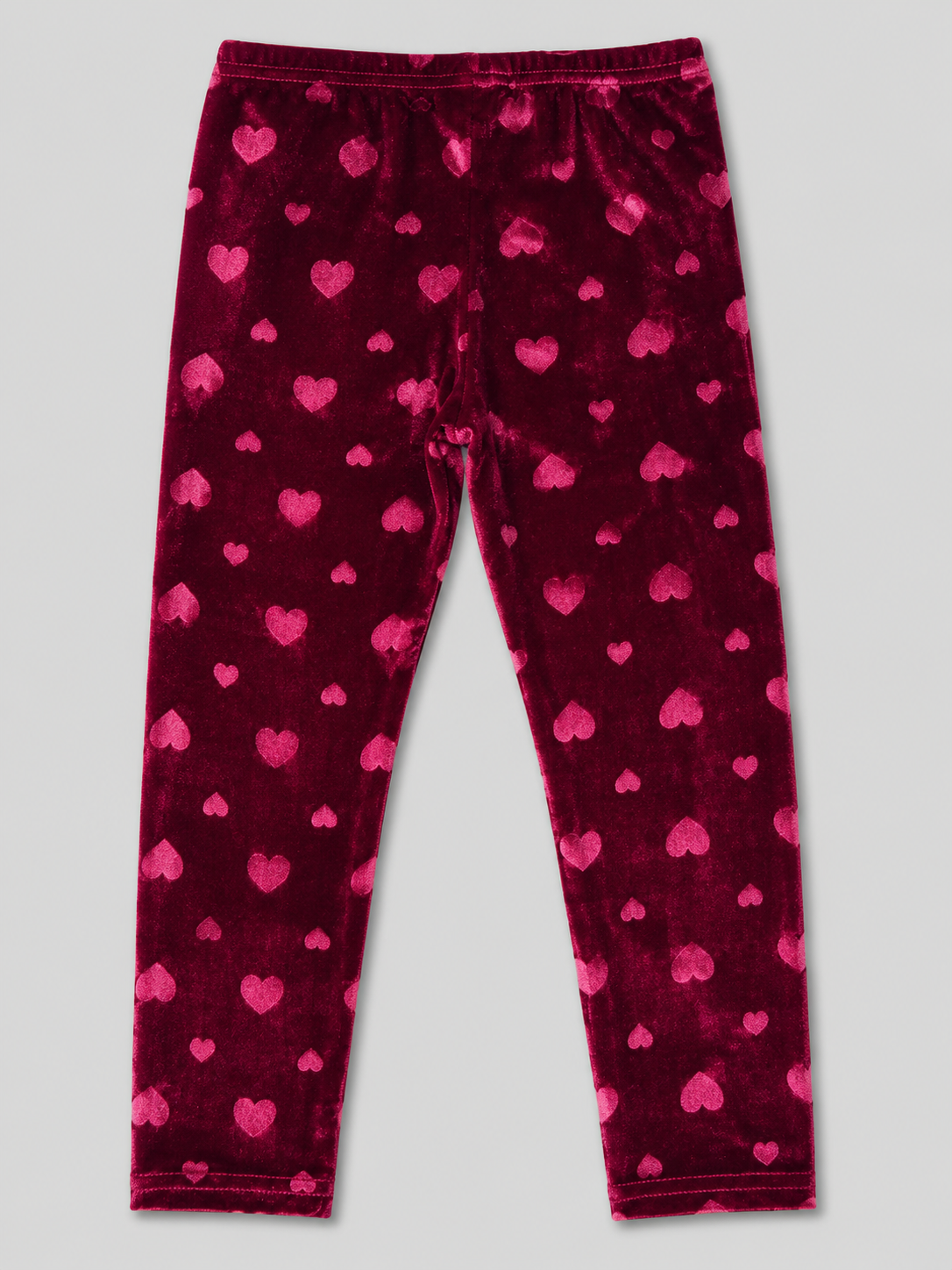 A pair of plush velvet leggings in deep magenta with an allover pattern of smaller pink hearts, laid flat against a light gray background.