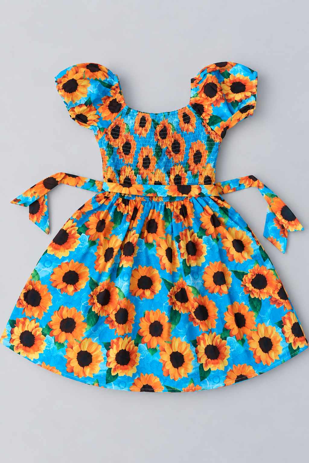 Back view of girls turquoise sunflower print dress with smocked bodice, puff sleeves and coordinating waist ties