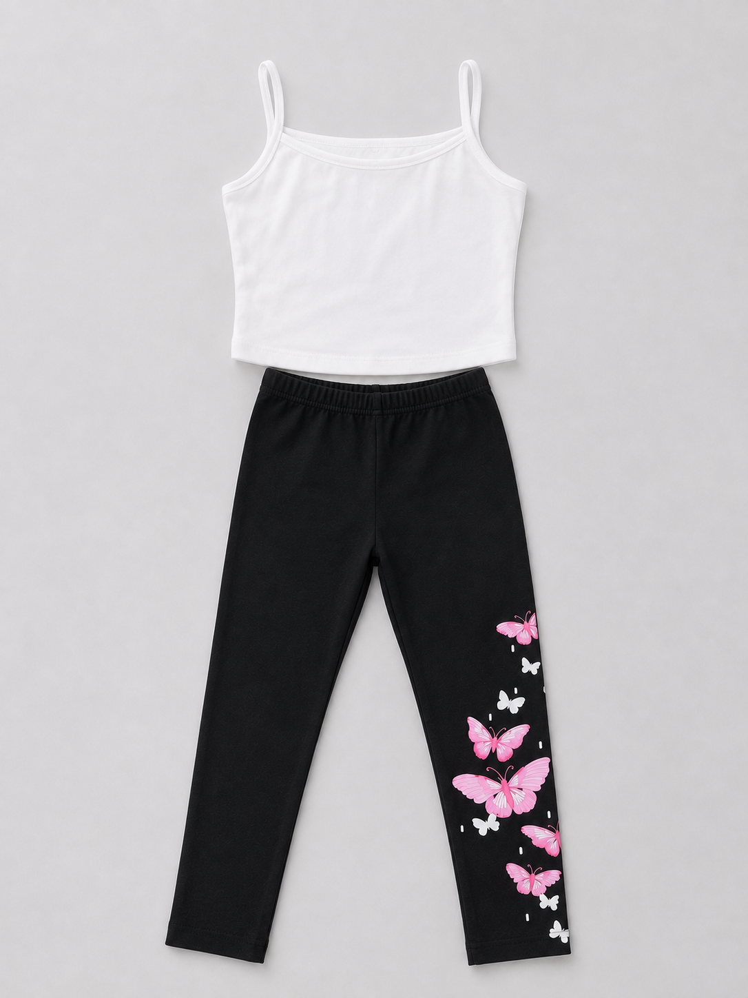 Shop this adorable girls’ two-piece outfit featuring a white camisole top and black leggings with a beautiful pink and white butterfly print. Perfect for everyday wear and casual outings.
