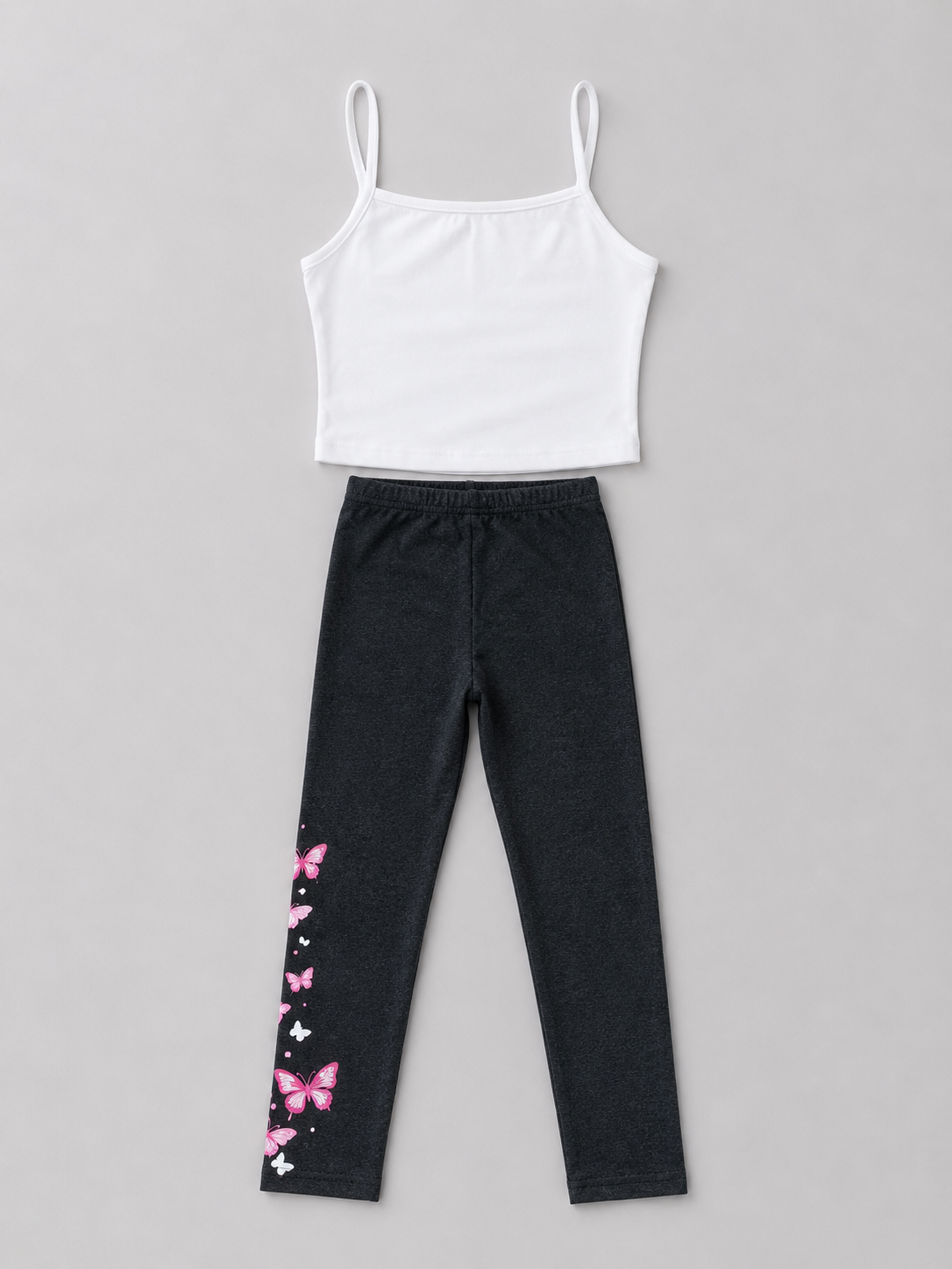 Shop this adorable girls’ two-piece outfit featuring a white camisole top and black leggings with a beautiful pink and white butterfly print. Perfect for everyday wear and casual outings.