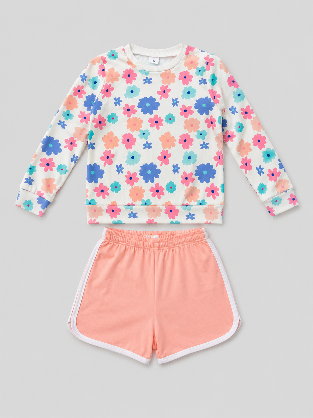 Shop this adorable girls’ two-piece set featuring a colorful floral long-sleeve top and coral shorts with white trim. Perfect for everyday wear, playdates, casual outings, and warm-weather activities.

