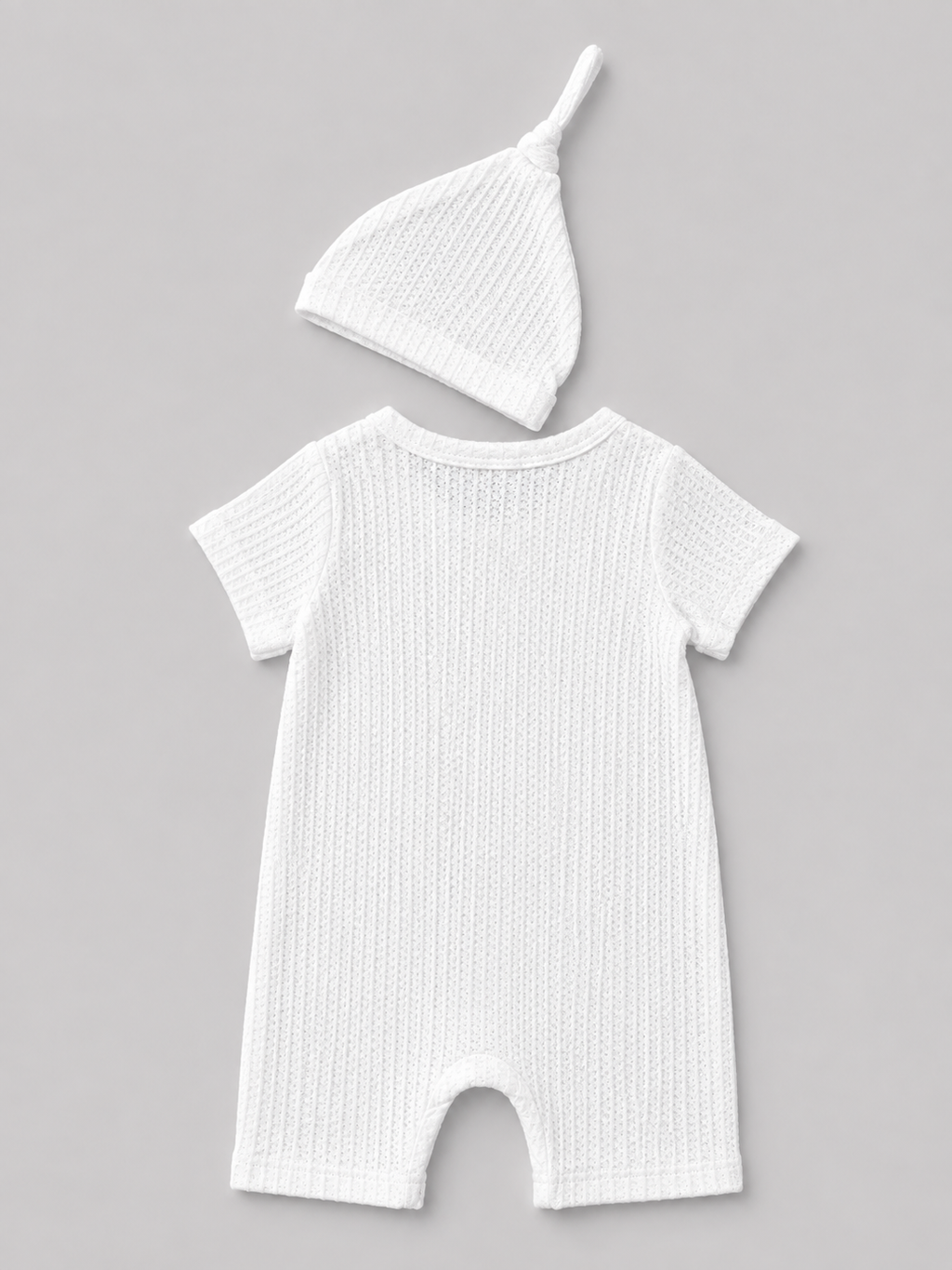 Shop this sweet white baby romper and matching knot hat set featuring textured fabric and an embroidered “Hello I’m new here” message. Perfect for newborn photos, coming-home outfits, and baby gifts.