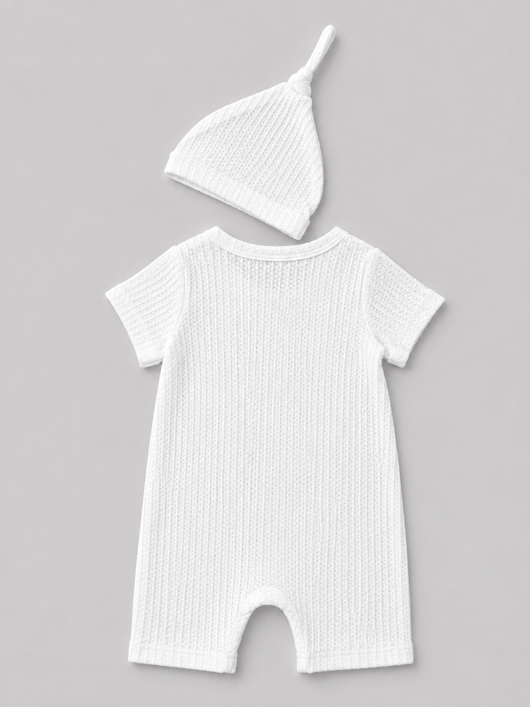 Shop this sweet white baby romper and matching knot hat set featuring textured fabric and an embroidered “Hello I’m new here” message. Perfect for newborn photos, coming-home outfits, and baby gifts.