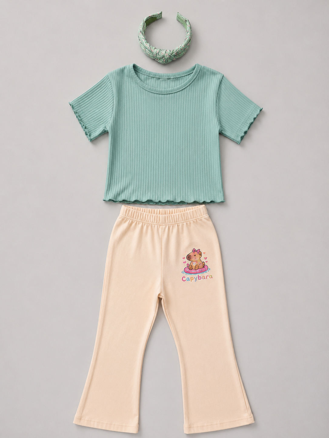 Shop this sage green and white striped girls blouse featuring a sleeveless design, gathered ruffle hem, and natural-tone back buttons. A fresh and versatile top for everyday wear, school, vacations, and special outings.