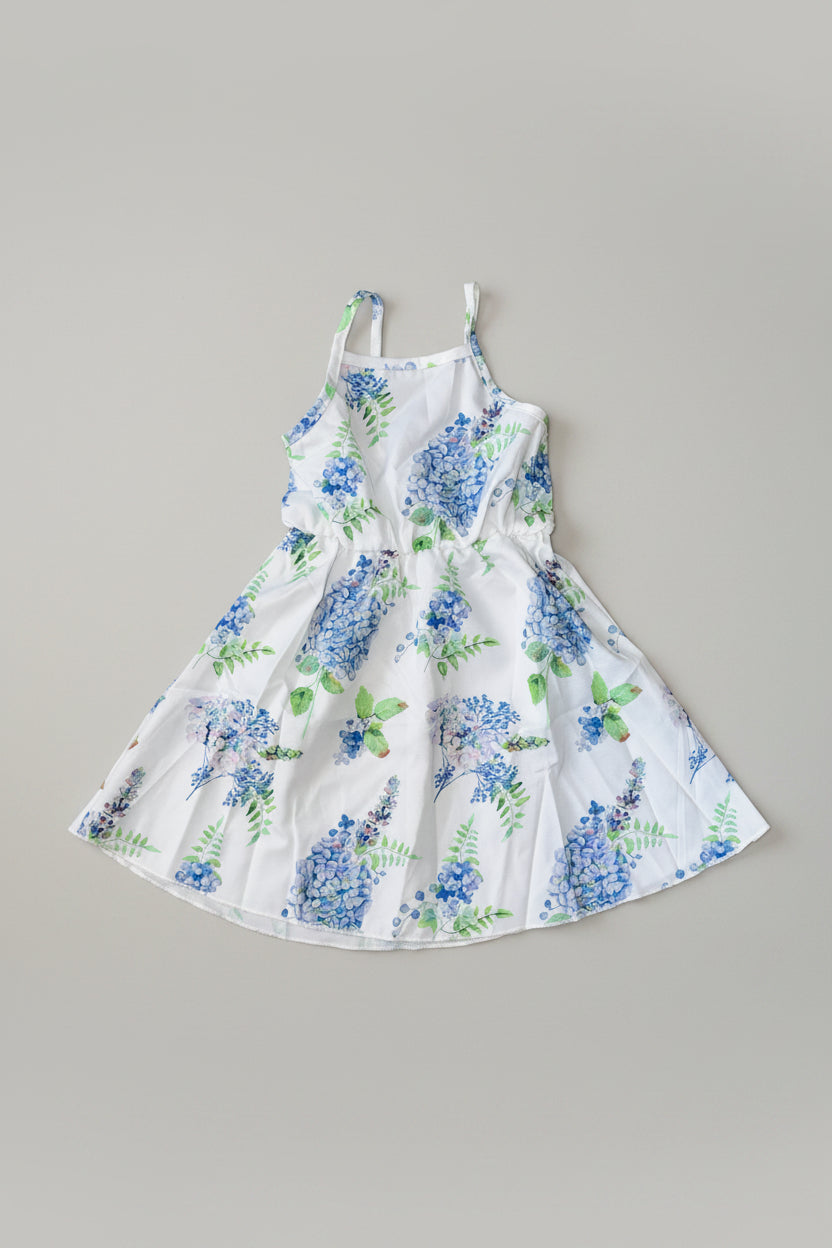 A white sleeveless sundress with a blue and green floral print.