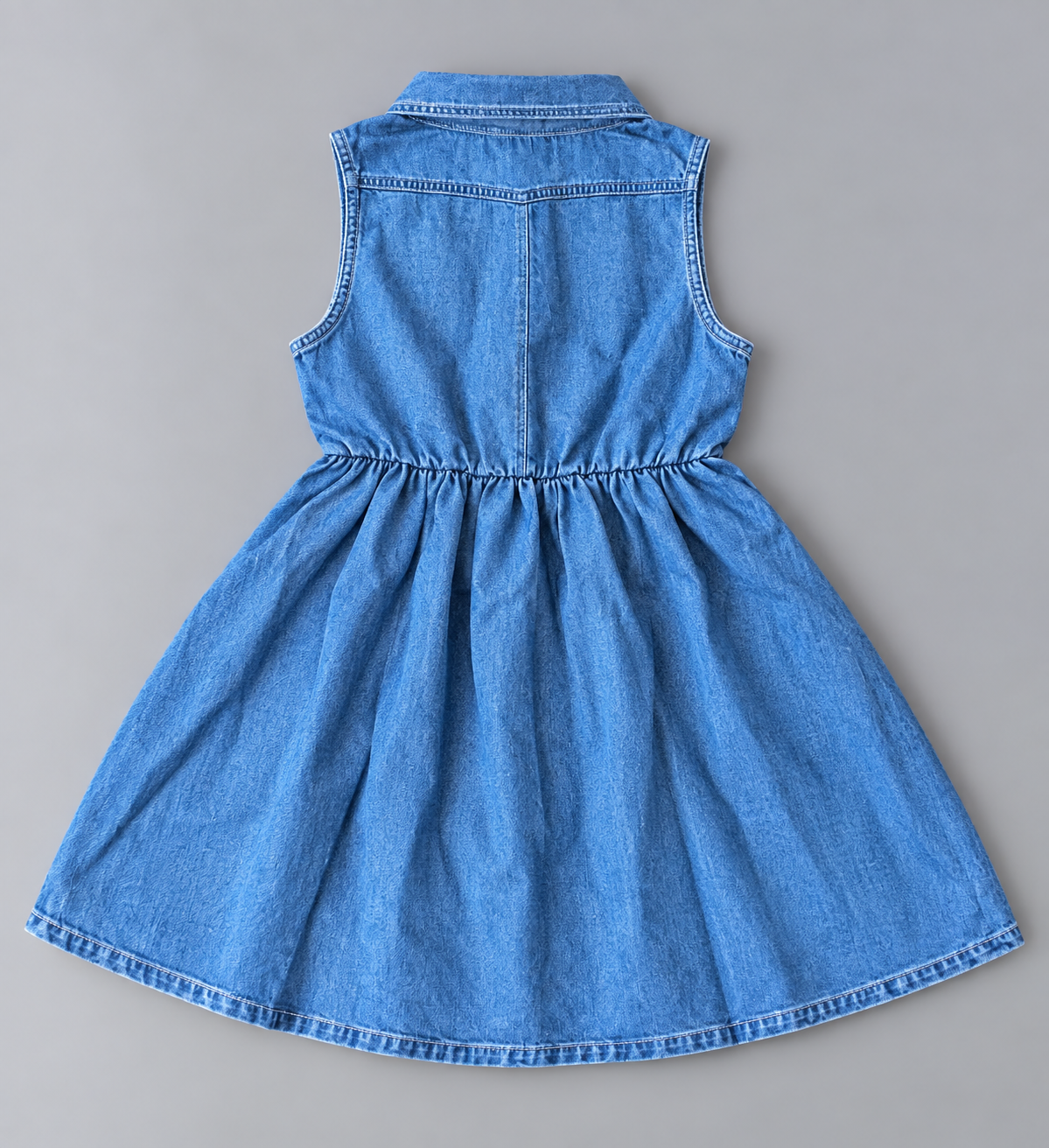 Back view of girls blue denim-style sleeveless collared dress with gathered waist and flared skirt