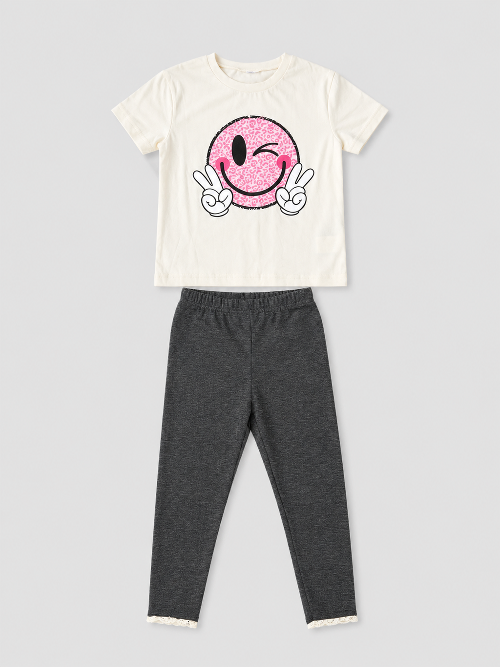 Girls ivory T-shirt with pink winking smiley face graphic and charcoal gray lace-trim leggings two-piece outfit, front view, size 4Y.