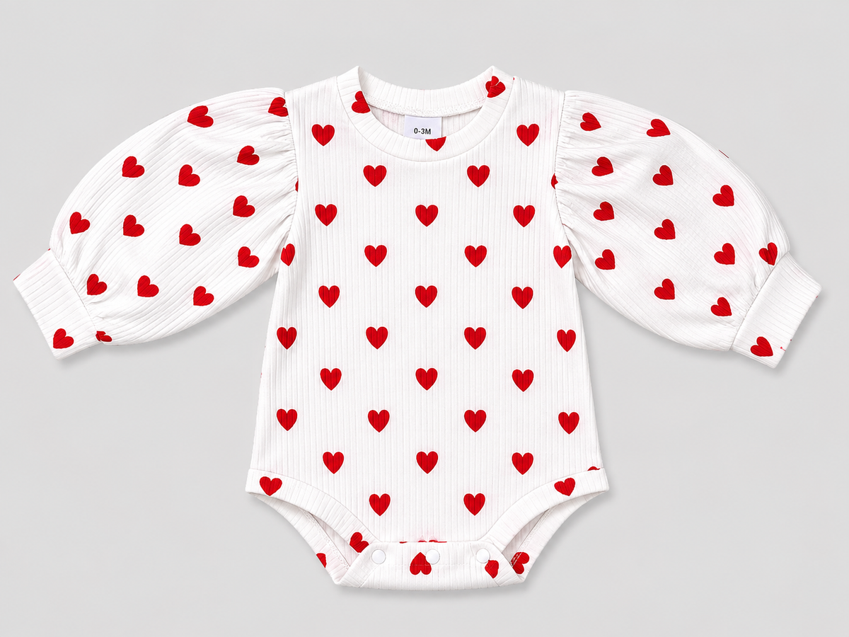 Adorable baby girls' white ribbed bodysuit featuring a red heart print, long puff sleeves, and snap closures. Soft, comfortable, and perfect for Valentine's Day or everyday wear.