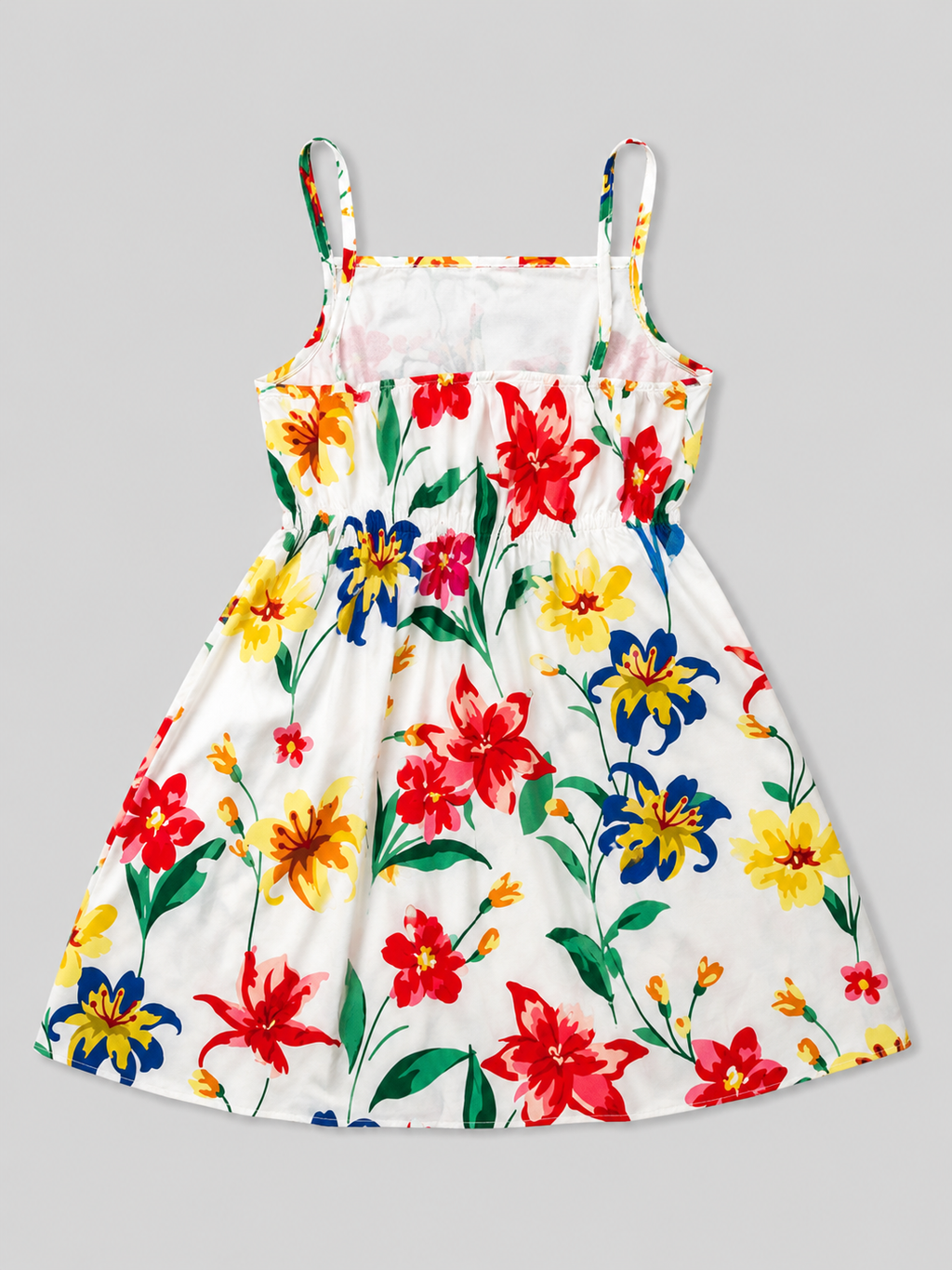 A white sleeveless sundress with thin shoulder straps, featuring a vibrant multicolor floral print with red, yellow, and blue flowers and green leaves, shown flat against a solid gray background.