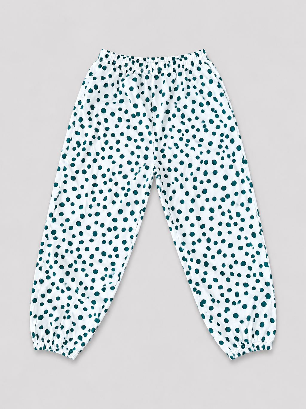 Girls white jogger pants with teal polka dot print, elastic waistband, and gathered ankle cuffs, front view, size 8–10Y.