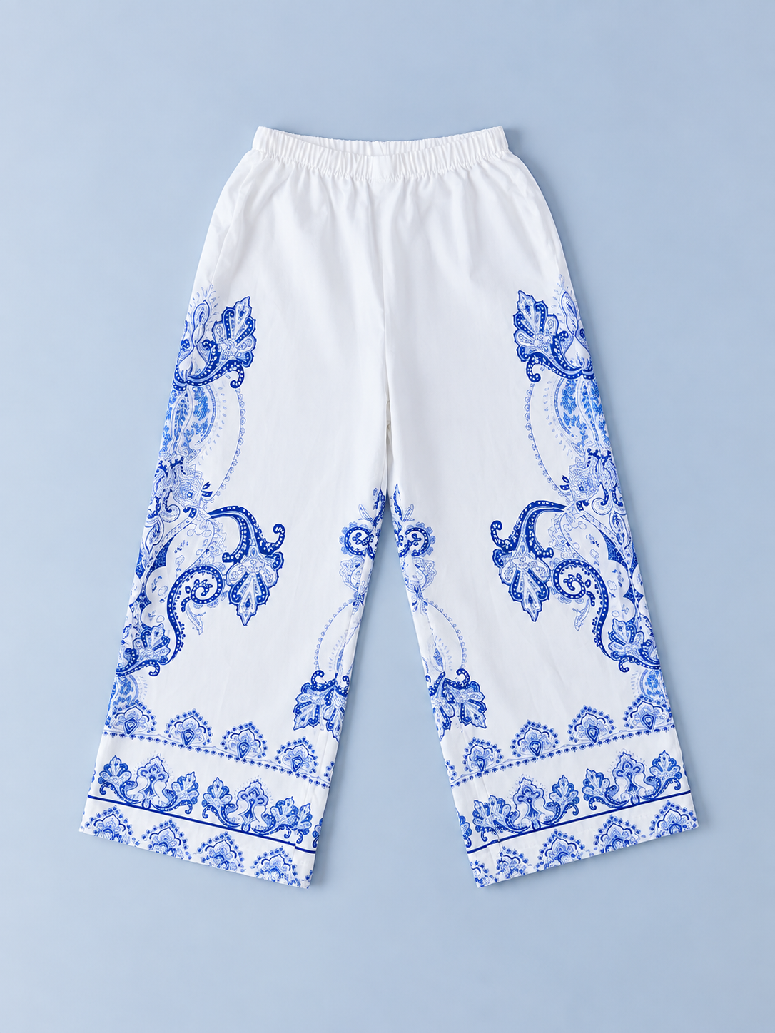 Girls white wide-leg pants with blue paisley-inspired border print and elastic waistband