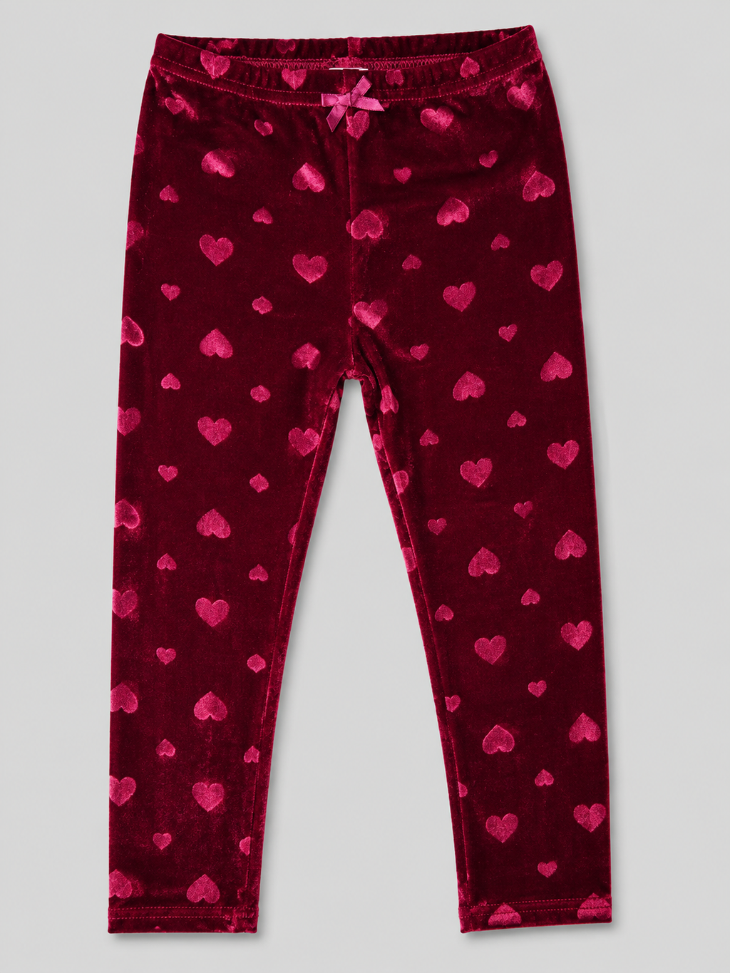 A pair of dark red velvet leggings with an all-over pink heart pattern, featuring an elastic waistband and a small bow at the center front, shown flat on a light gray background.