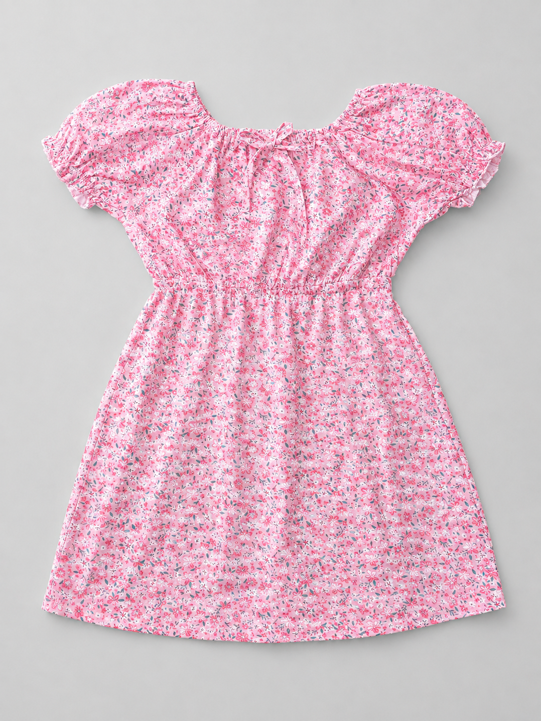 A pink and white floral print babydoll dress with short puff sleeves, a smocked bodice, and a ruffled neckline, shown flat on a neutral gray background.