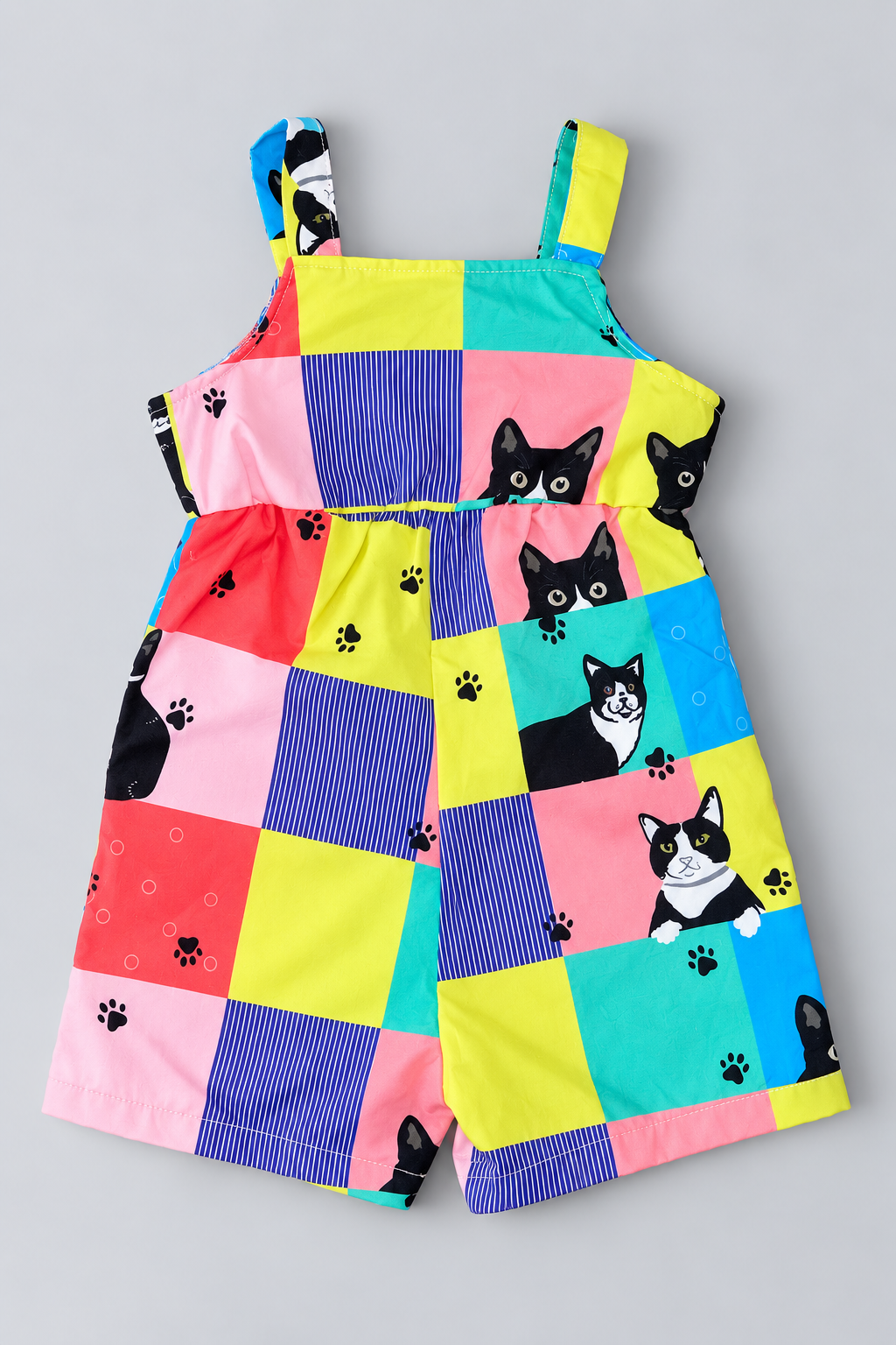 Back view of colorful baby romper with patchwork cat print, wide shoulder straps and gathered waist